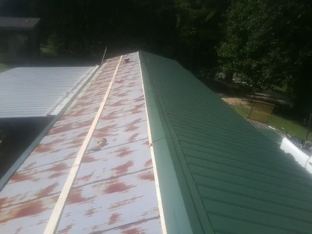Old rusted panels beside newly installed green metal roofing — Wind Damage Roof Repair by Roofing Brothers in South Dayton
