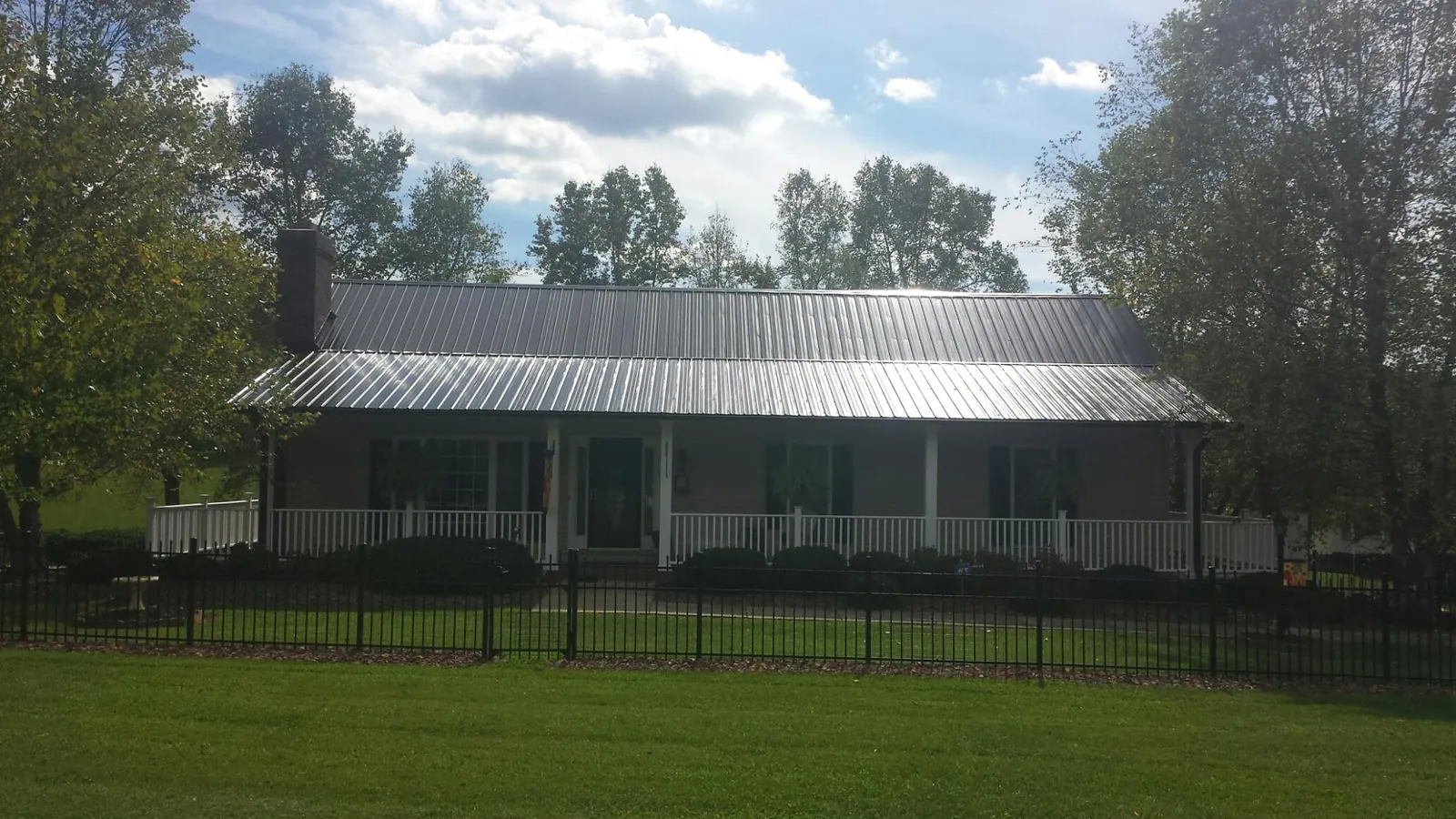 Gray metal roof on a brick ranch with a full width front porch — Gutter Guard Installation work by our crew in South Dayton