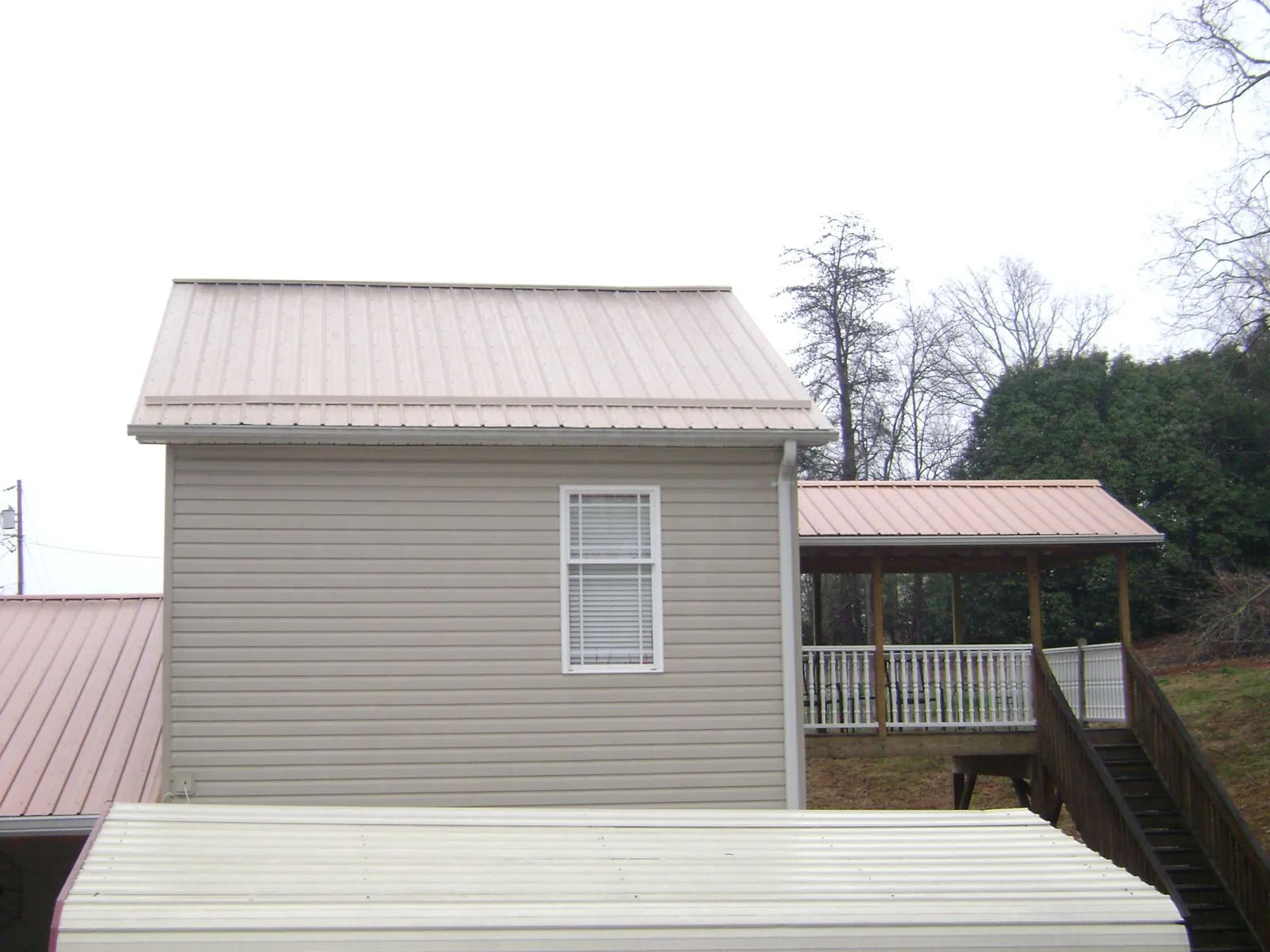 Tan metal roofs on a two story addition and attached porch, from a Roof Replacement job in South Dayton