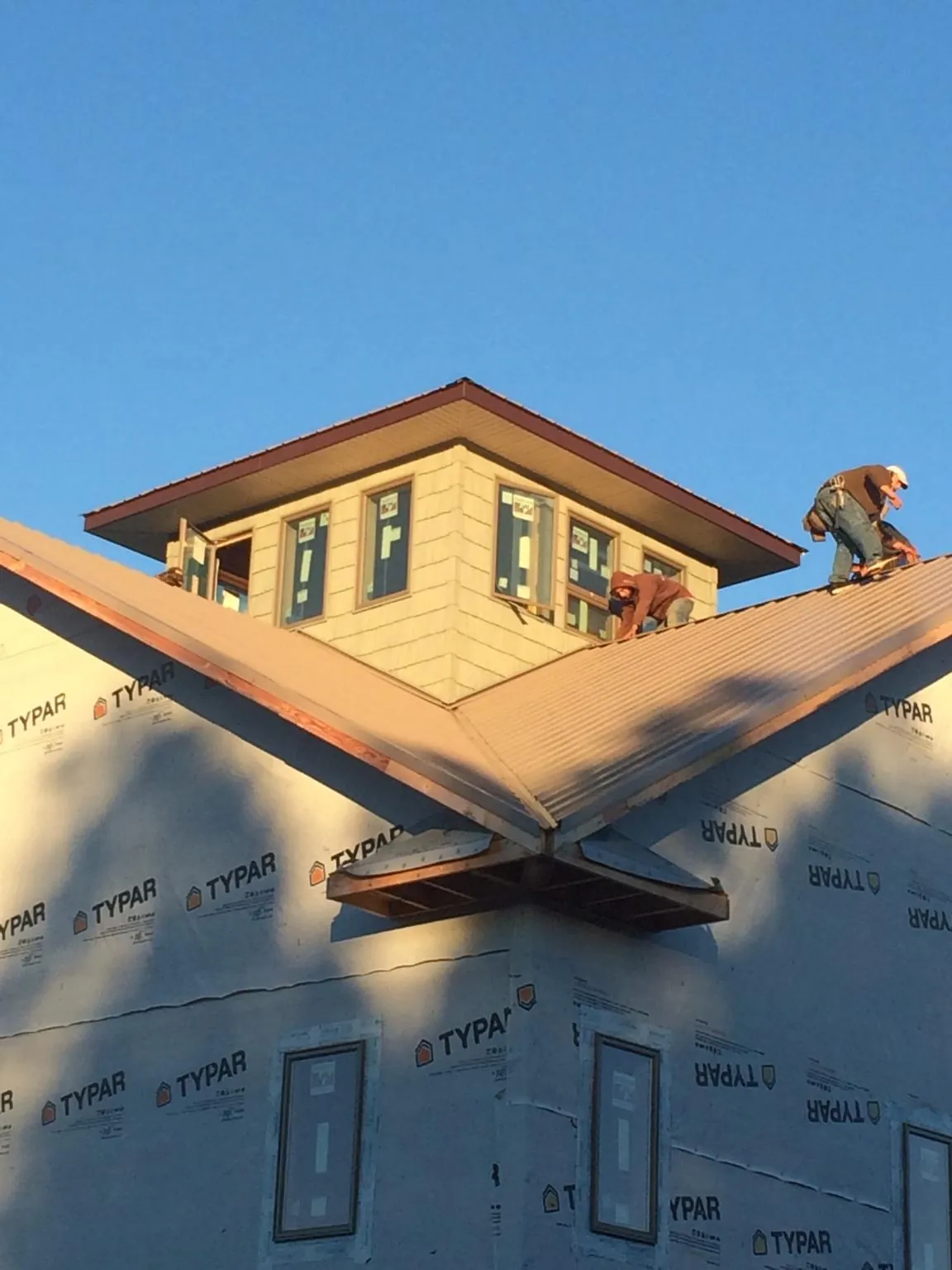 Roofers working around a rooftop cupola on a new metal roof at sunset — Roof Waterproofing in South Dayton by Roofing Brothers